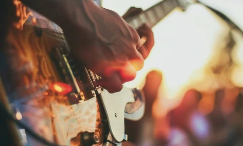 electric-guitar-closeup-summer-gig-stage-flare-sharp-focus-crowd-out-focus-side-space